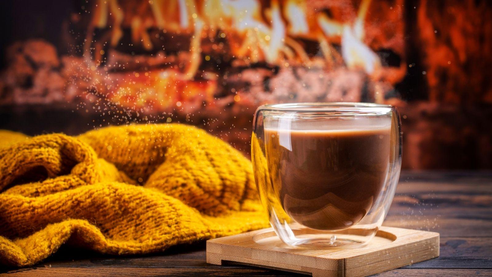 slow down and have a hot chocolate. image shows a log fire, a yellow ochre blanket and a hot chocolate in a glass