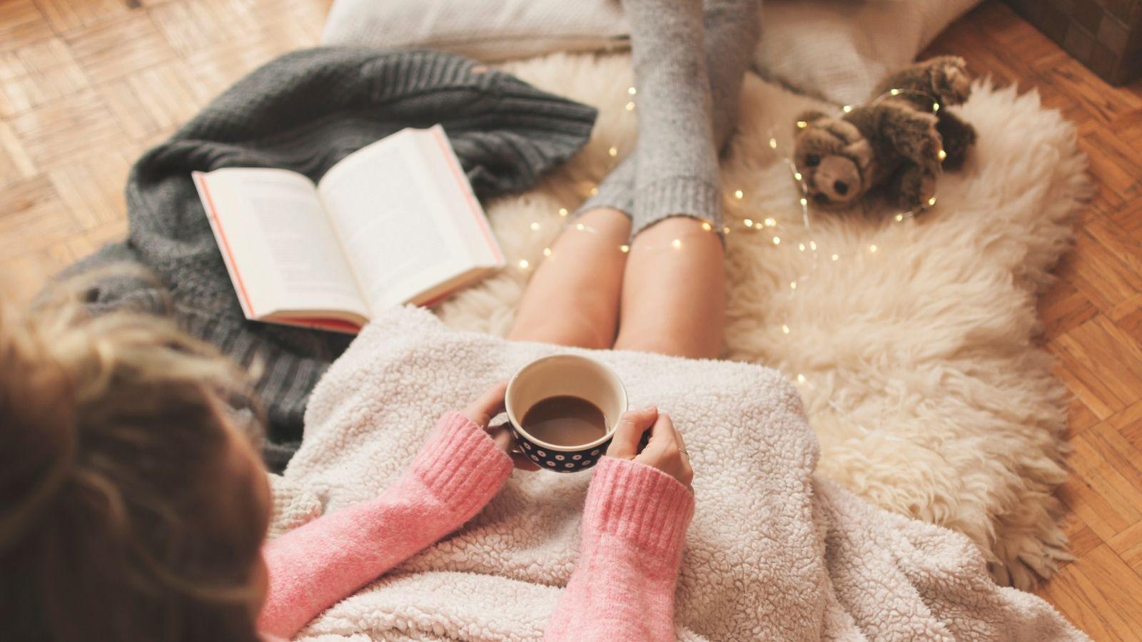 Slow down and have an early night. Image shows picture of a woman in fluffy socks with a book and a hot drink