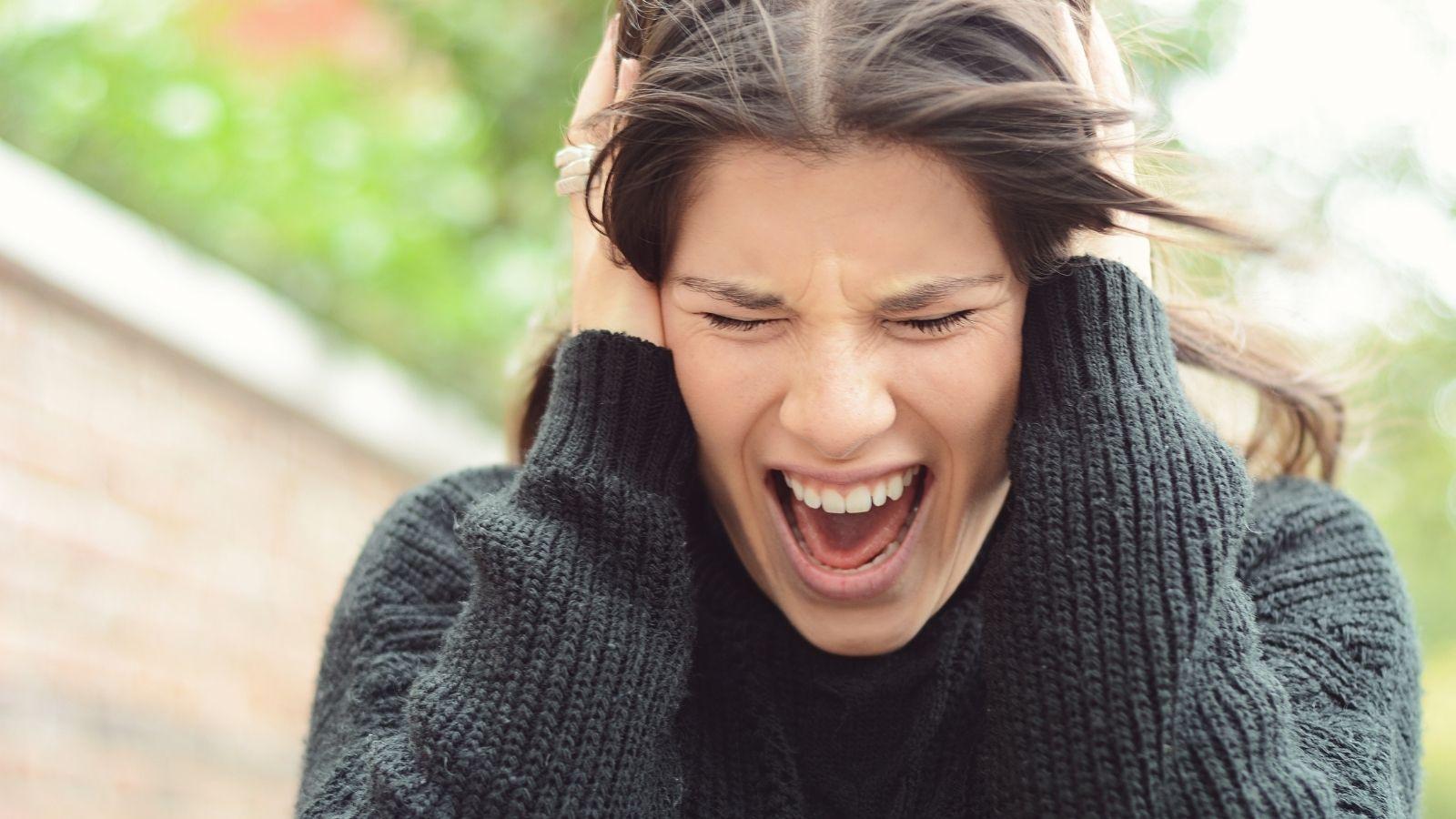 Image of woman holding her head and screaming with symptoms of stress