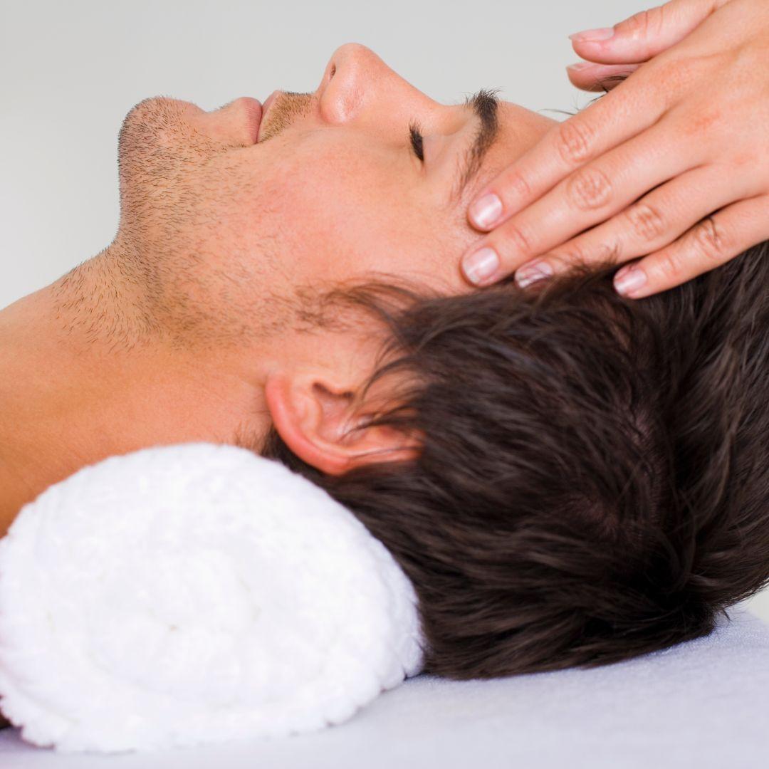 Indian Head Massage. image of man laying on a towel having his head rubbed