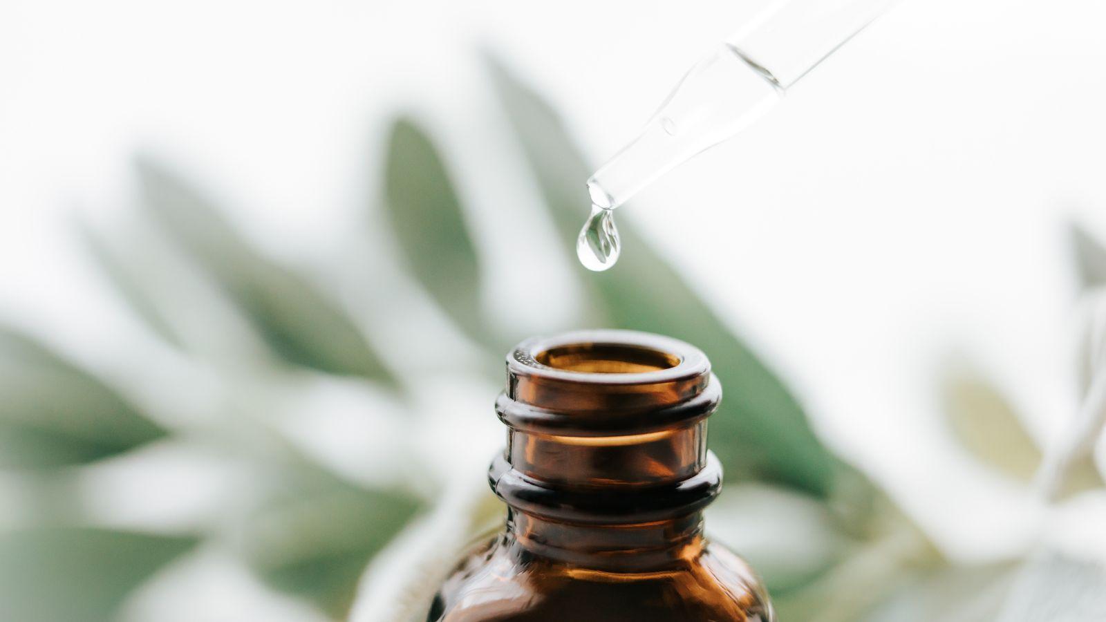 essential oils to relieve headaches. Image of a bottle of essential oil with a leaf in the background