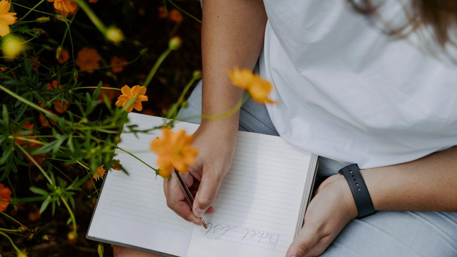 Summer energy make a list. Image of woman in a white dress with a note book and dandelions making a bucket list