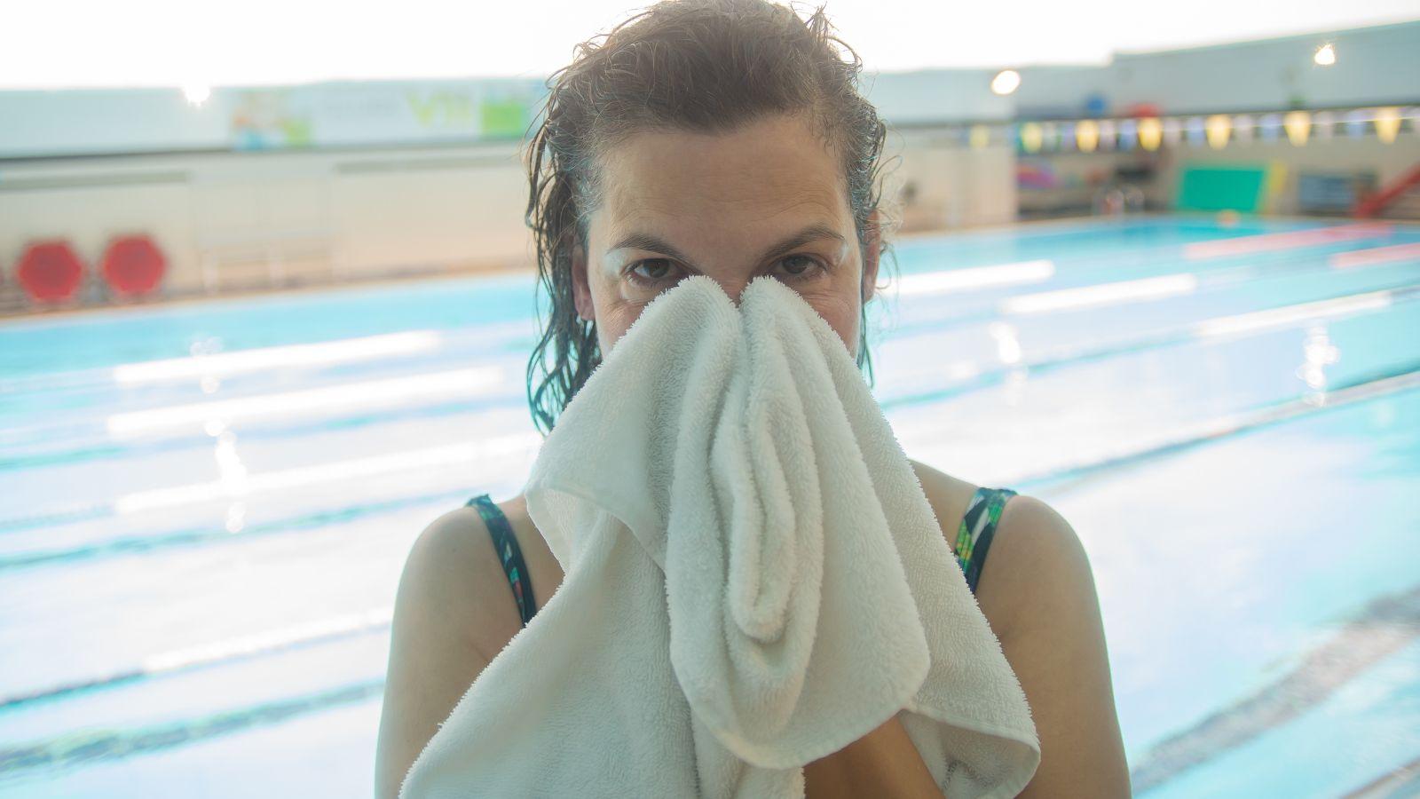 Summer energy keep your swimming kit in your car. Image of woman by a swimming pool wiping her face with a light coloured towel