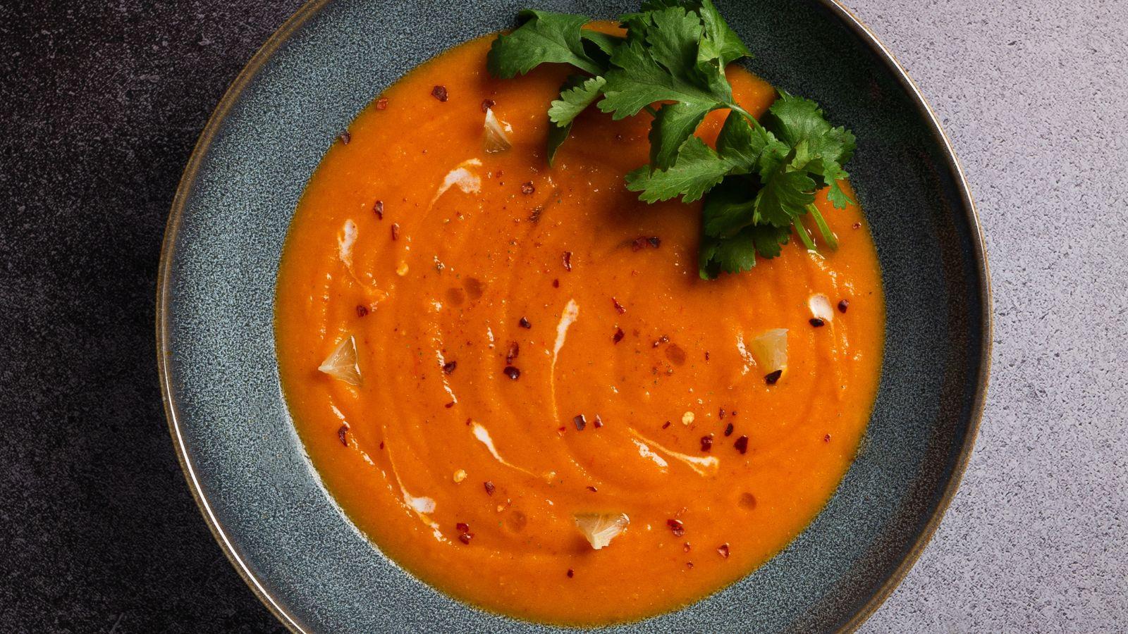 image of some homemade tomato and red pepper soup in a black bowl to depict autumn