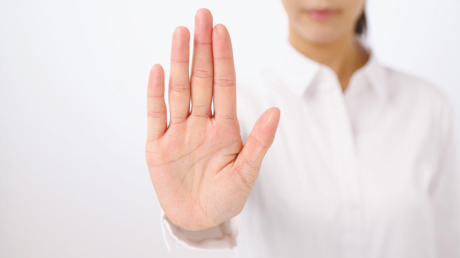 image of a woman with her hand up showing that she is assertive to illustrate how to be a goddess