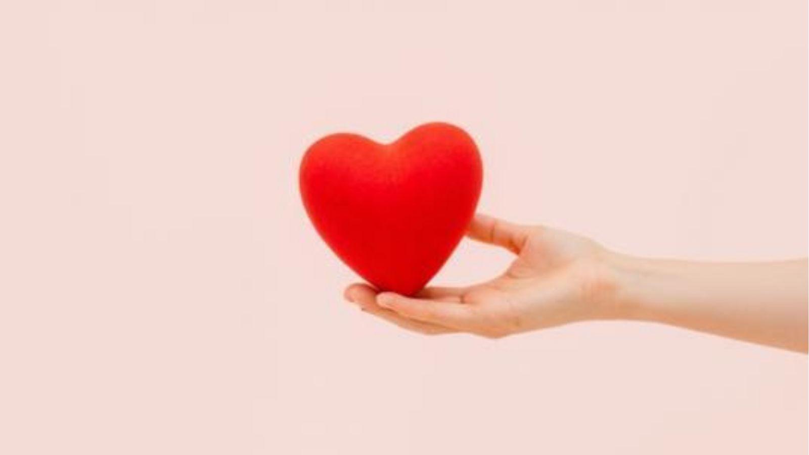 vetiver essential oil is an aphrodisiac Image of a woman holding a love heart on a pink background