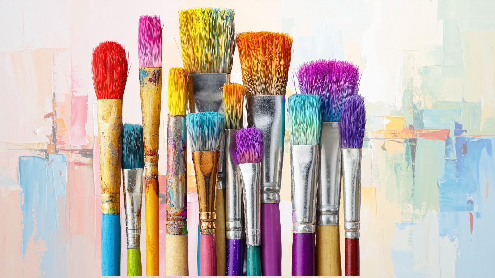 creative image of brightly coloured paint brushes of varying sizes on a painted background